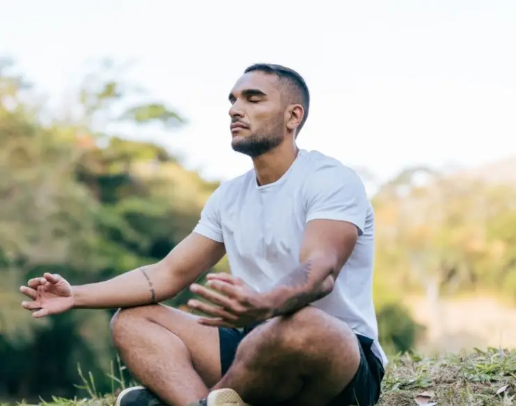 Athlete meditating in the public park on a sunny day
