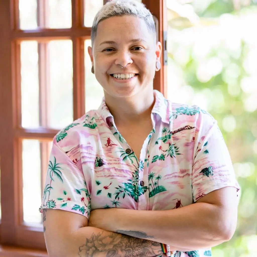 Portrait of cheerful mid adult woman with her arms crossed standing by window at home looking at camera and smiling